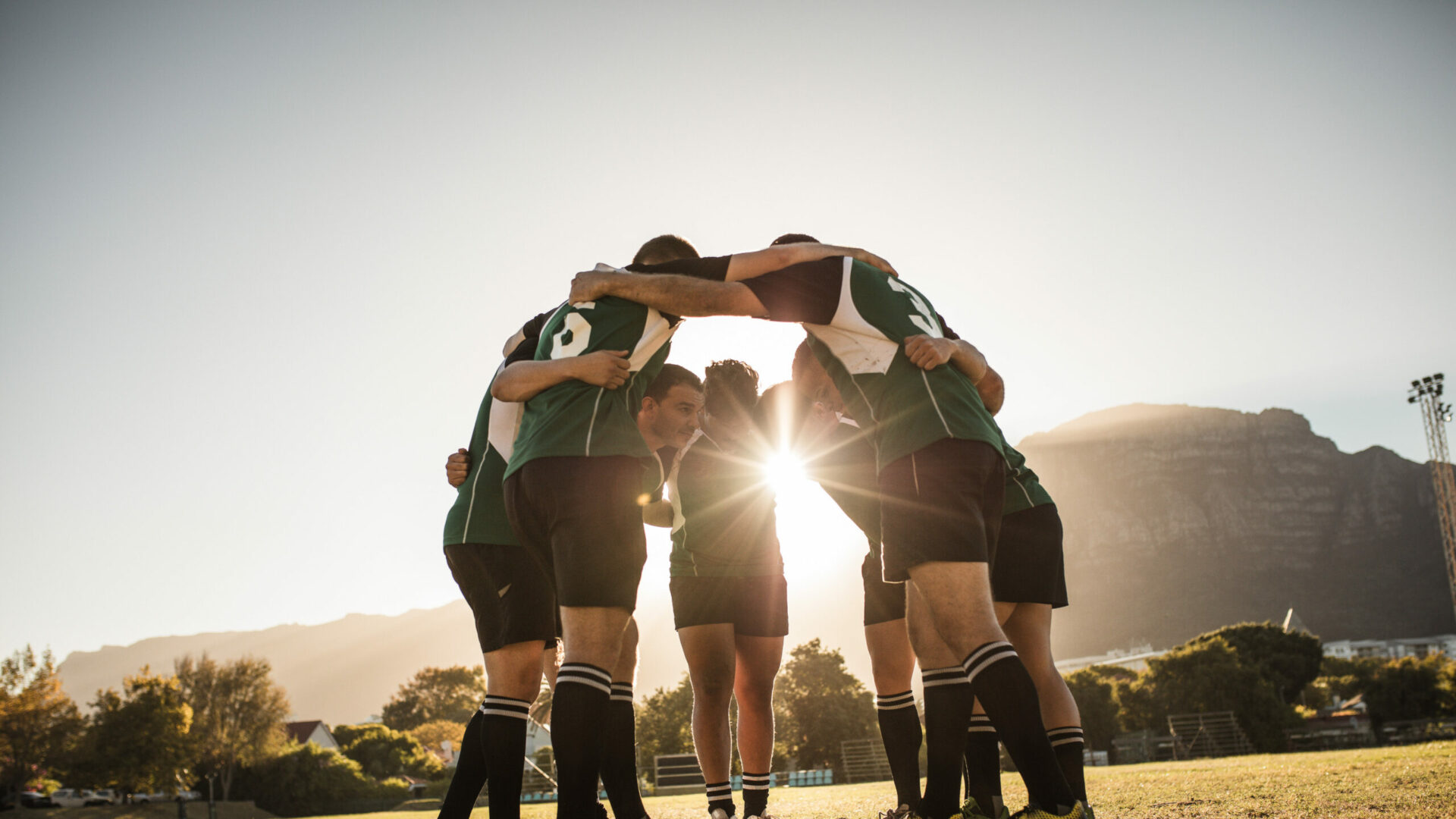 Image d'une équipe de rugby se tenant en cercle sur un terrain