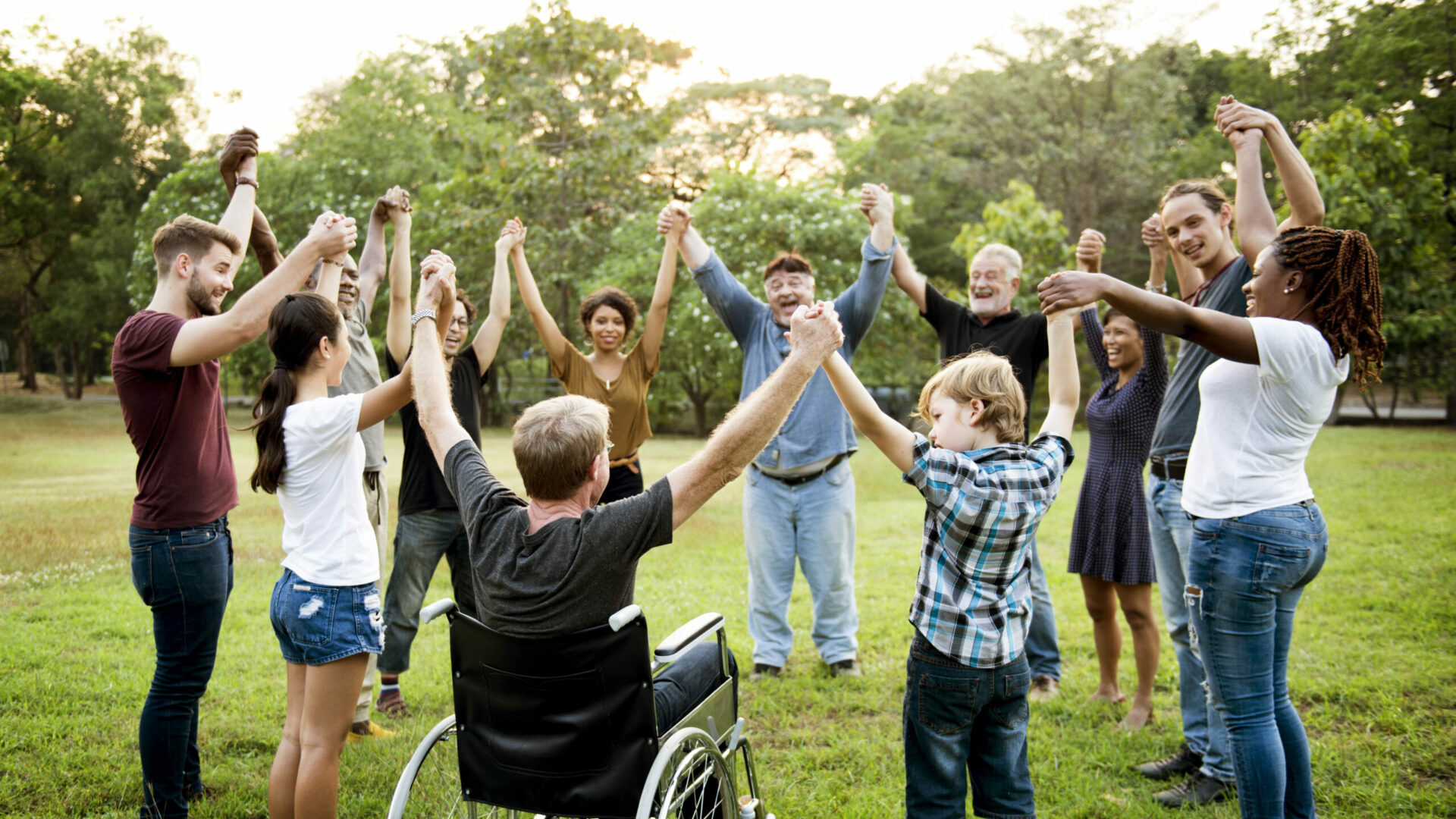 Image de plusieurs personnes en cercle de différents âges, sexe, cultures, se tenant et levant les mains